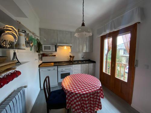 cocina con mesa y mantel rojo y blanco en Casa Prada en Sanabria, en Sotillo de Sanabria