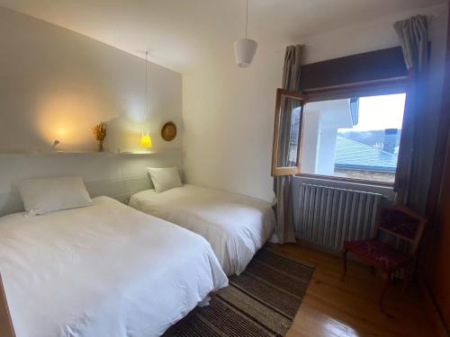 1 dormitorio con 2 camas, ventana y silla en Casa Prada en Sanabria, en Sotillo de Sanabria