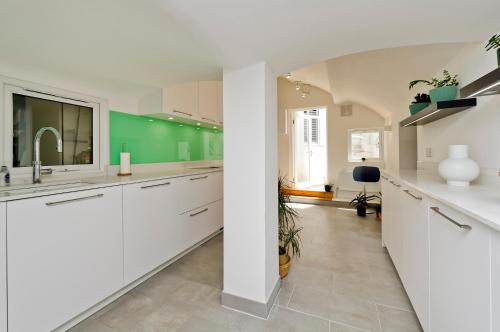 uma cozinha com armários brancos e uma parede verde em Beautiful Battersea Home by Clapham Junction by UnderTheDoormat em Londres