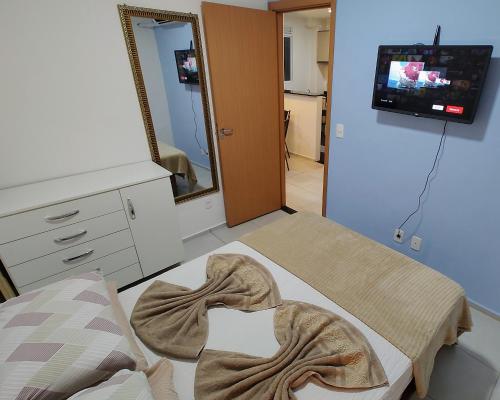 een kamer met een bed, een spiegel en een tv bij Apto Executivo Ravena II in Campo Grande