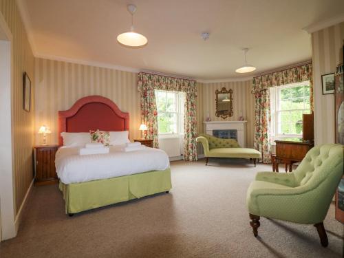 a bedroom with a large bed and two chairs at Glamis House in Forfar