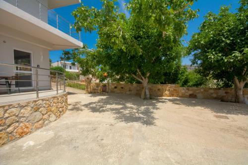 a house with a tree and a stone wall at Arismari House in Ravdhoúkha