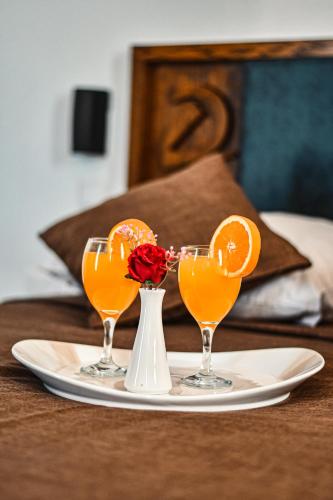 two glasses of orange juice and a vase with a rose at Dorana Hotel in Kérynia