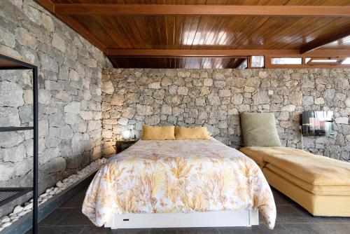 a bedroom with a bed and a stone wall at La Casita de la Orilla de Peñate in Santa Brígida