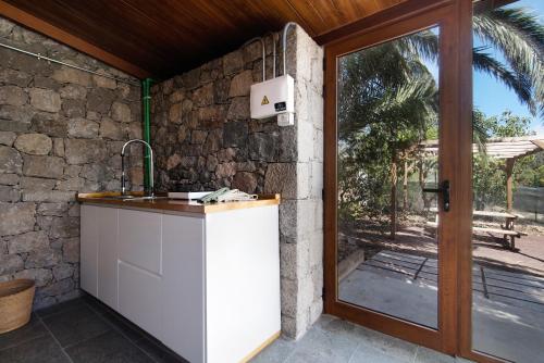 a kitchen with a sink next to a stone wall at La Casita de la Orilla de Peñate in Santa Brígida