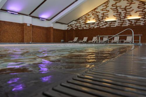 an indoor swimming pool with chairs in a building at Ruskovets Thermal SPA & Ski Resort in Bansko