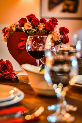 a table with a glass of wine and a vase of roses at Dorana Hotel in Kérynia