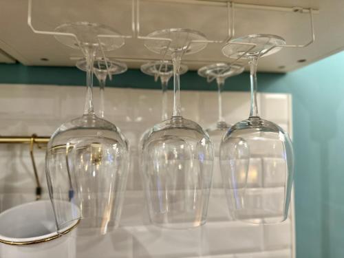 four wine glasses hanging from a rack in a kitchen at Aquarium Exclusive Loft - Free Parking in Genova