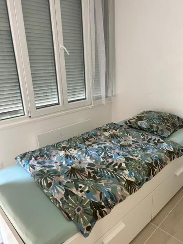 a bed with a blanket on it with two windows at Studio3 Centre ville Massy in Massy