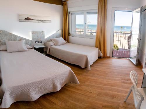 two beds in a room with a view of the ocean at Hotel Playa in Peñíscola