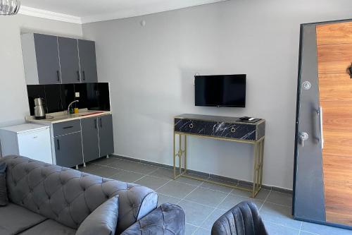 ein Wohnzimmer mit einem Sofa und einem Tisch mit einem TV in der Unterkunft Simlarda Country Club Ayvalık in Ayvalık