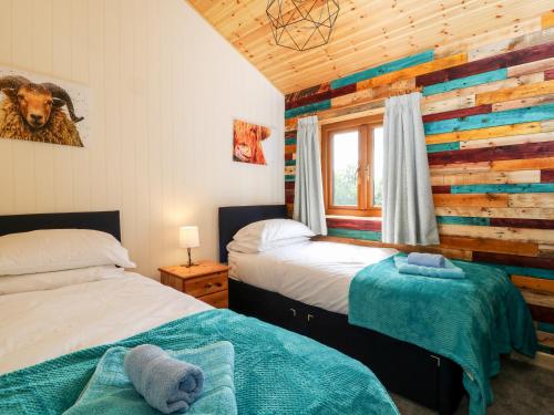 a bedroom with two beds and a wooden wall at The Great Escape in Beaworthy