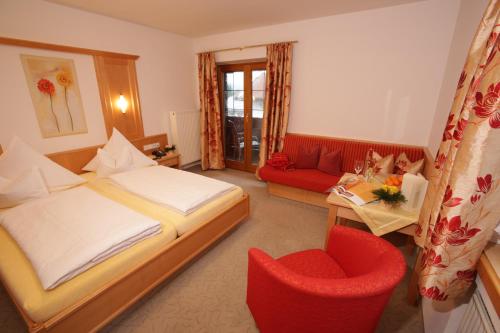 ライト・イム・ヴィンクルにあるGästehaus Pretznerのベッドと赤い椅子が備わるホテルルームです。
