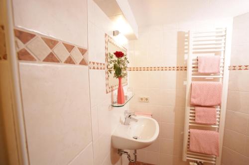 ein Badezimmer mit einem Waschbecken und einer Vase mit einer Rose in der Unterkunft Gästehaus Pretzner in Reit im Winkl