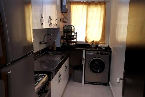 a small kitchen with a washing machine and a window at Un appartement à proximité de la corniche Hoceima pour les familles in Al Hoceïma