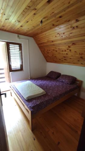 a bed in a room with a wooden ceiling at Apartman Mitrić in Šipovo