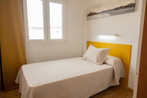 a bedroom with a bed with a yellow headboard and a window at Hotel Playa in Peñíscola