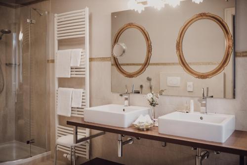 a bathroom with two sinks and two mirrors at Hotel Adria in Merano