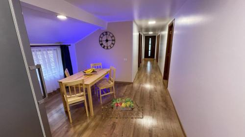 a dining room with a table and chairs and a clock at Casa Tudor in Tîrgu Ocna