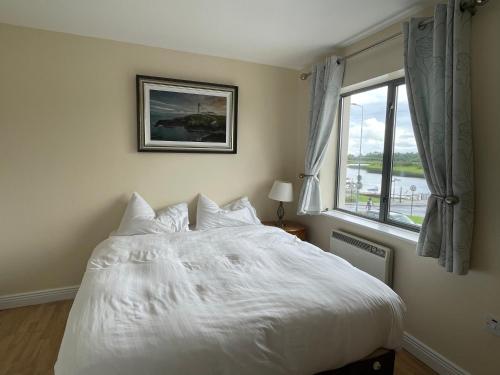 1 dormitorio con cama blanca y ventana en Waterfront View Apartment, en Carrick on Shannon