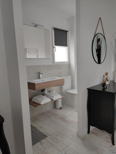 une salle de bain blanche avec un lavabo et un miroir dans l'établissement La Parenthèse Cormillonne, à Corme-Écluse