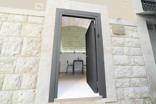 a door in a brick wall with a table behind it at LE PUGLIE LUXURY APARTMENTS in Molfetta
