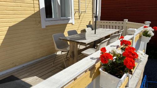 a wooden table and chairs on a porch with red flowers at Krepelin Apartments in Kristiinankaupunki