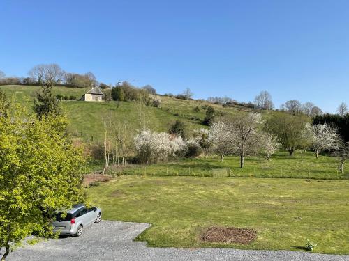a car parked in a parking lot next to a field at Grande Chambre Familiale VERTE Tout Bonnement Bien in Putot-en-Auge