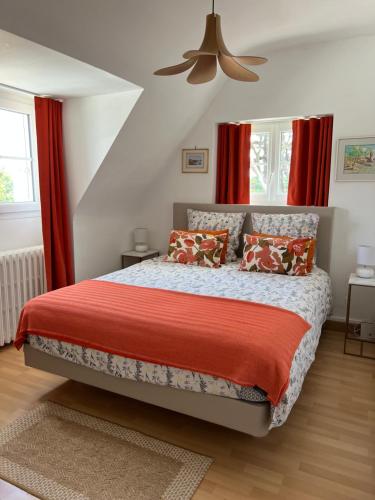 a bedroom with a bed with red curtains and a fan at Kerloulou in Poullan-sur-Mer