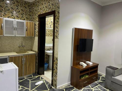 a bathroom with a sink and a television in a room at رمال الجزيره in Al Ḩawīyah