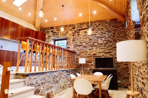 a dining room with a stone wall and a table and chairs at Casa do avô tamanqueiro in Arco de Baúlhe