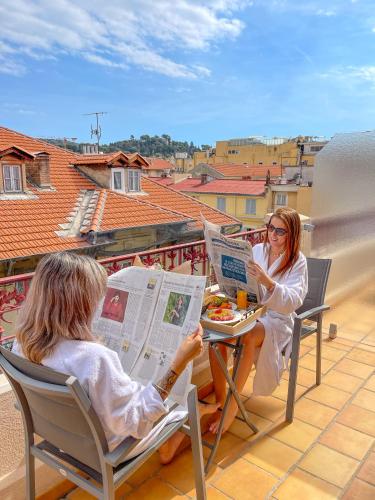 two people sitting at a table reading a newspaper at Best Western Plus Hôtel Massena Nice in Nice