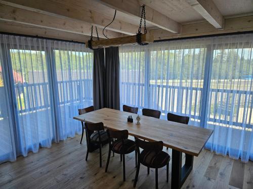 einen Holztisch und Stühle in einem Zimmer mit großen Fenstern in der Unterkunft Chata Paja in Liptovský Mikuláš
