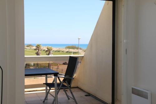 d'une table et d'une chaise sur un balcon avec vue sur la plage. dans l'établissement Studio 232, Héliopolis AB au village naturiste, au Cap d'Agde