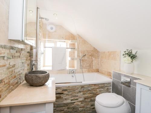a bathroom with a tub and a toilet and a sink at 2 Dewars Farm Cottages in Bicester