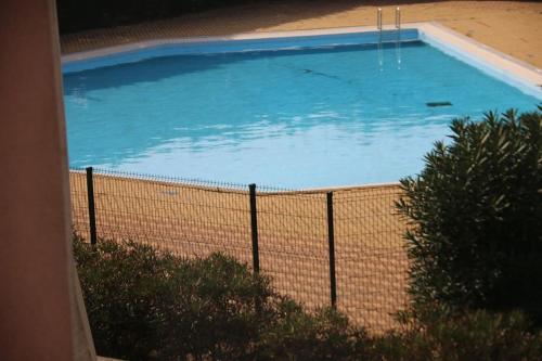 une grande piscine bleue derrière une clôture dans l'établissement Studio 216, Port Vénus au village naturiste, au Cap d'Agde