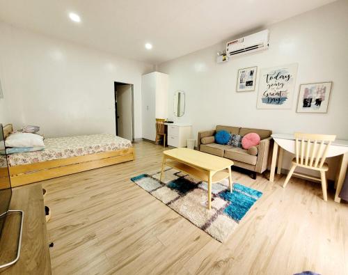 a bedroom with a bed and a couch and a table at CAP Apartments in Talibon