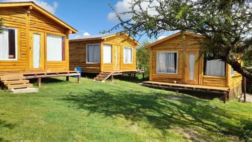 a couple of wooden lodges in a yard at Complejo majua in Cosquín