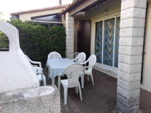 une table blanche et des chaises sur une terrasse dans l'établissement Villa 12, Port Vénus au village naturiste, au Cap d'Agde