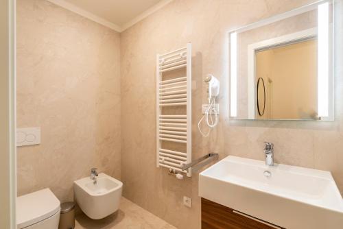 a bathroom with a sink and a toilet and a mirror at Petrin Tower Residence in Prague