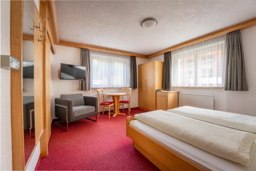 Hotel Garni Krumbach في دامولس: غرفه فندقيه بسرير وكرسي وطاولة