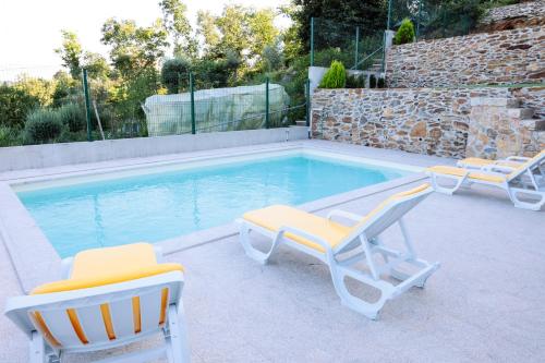 two chairs and a swimming pool with two chairs at Casa do avô tamanqueiro in Arco de Baúlhe