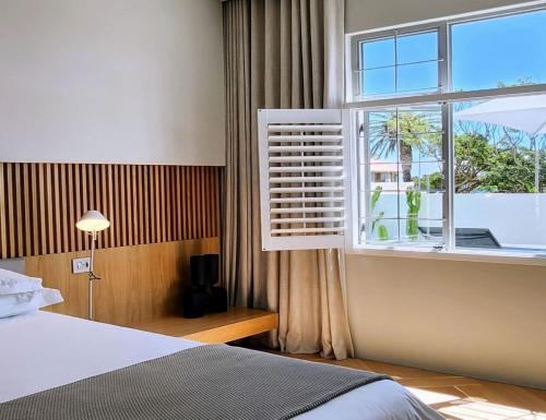 a bedroom with a bed and a large window at South Beach Camps Bay Boutique Hotel in Cape Town