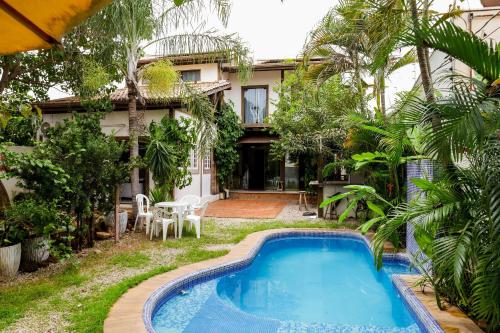 a villa with a swimming pool in front of a house at Pousada dos Bosques - Refúgio Urbano in Cuiabá