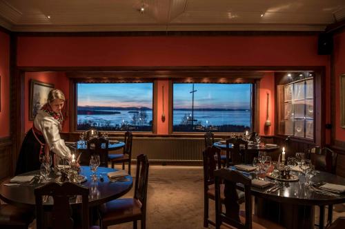 a woman standing in a room with tables in a restaurant at Green Hotel in Tällberg
