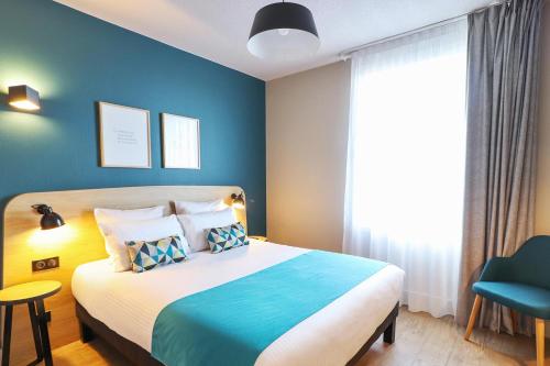 a bedroom with a bed and a blue wall at Appart'City Confort Toulouse Diagora Labège in Labège