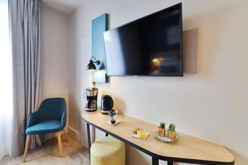 a hotel room with a desk and a television on a wall at Appart'City Confort Toulouse Diagora Labège in Labège