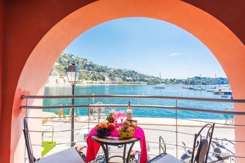 une table sur un balcon avec vue sur l'eau dans l'établissement LA RESERVE AP4369 By Riviera Holiday Homes, à Villefranche-sur-Mer