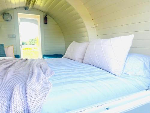 Bett mit weißer Bettwäsche und Kissen in einem Zimmer in der Unterkunft Charming Lodge in Morpeth in Morpeth
