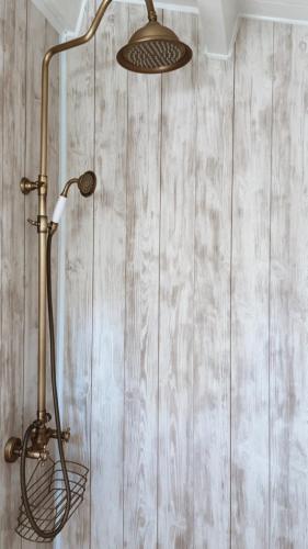 a shower head in a bathroom with a wooden wall at Ambercoast in Jūrmala